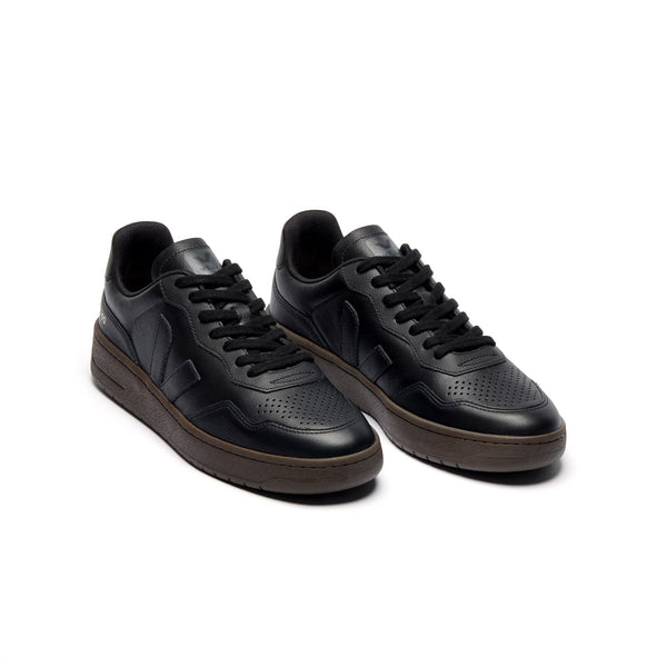 Three-quarter view of eco-friendly VEJA V-90 O.T. Leather unisex sneakers with black leather and eagle accents