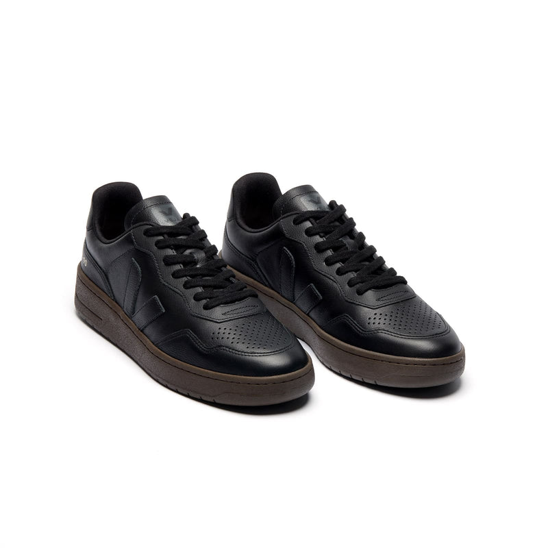 Three-quarter view of eco-friendly VEJA V-90 O.T. Leather unisex sneakers with black leather and eagle accents